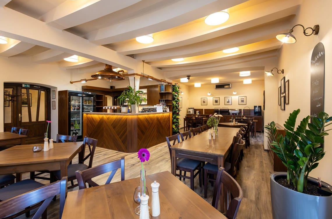 Interiér restaurace Turistických známek v Rýmařově s dřevěnými stoly a barem